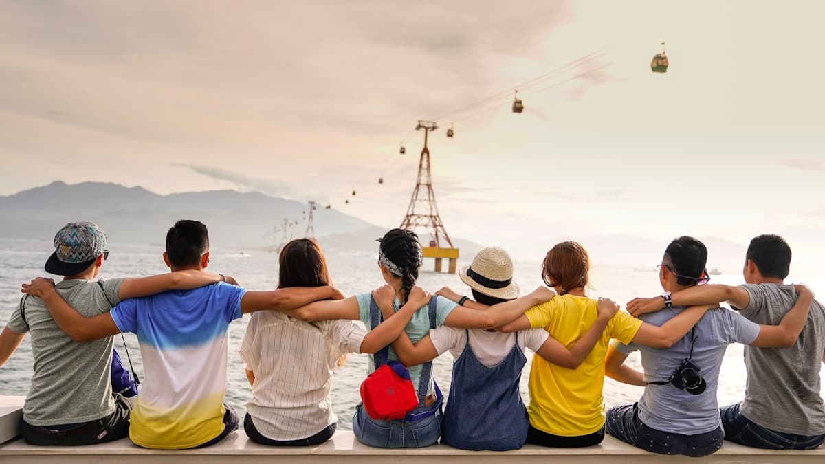 A row of friends sitting arm in arm, facing the water