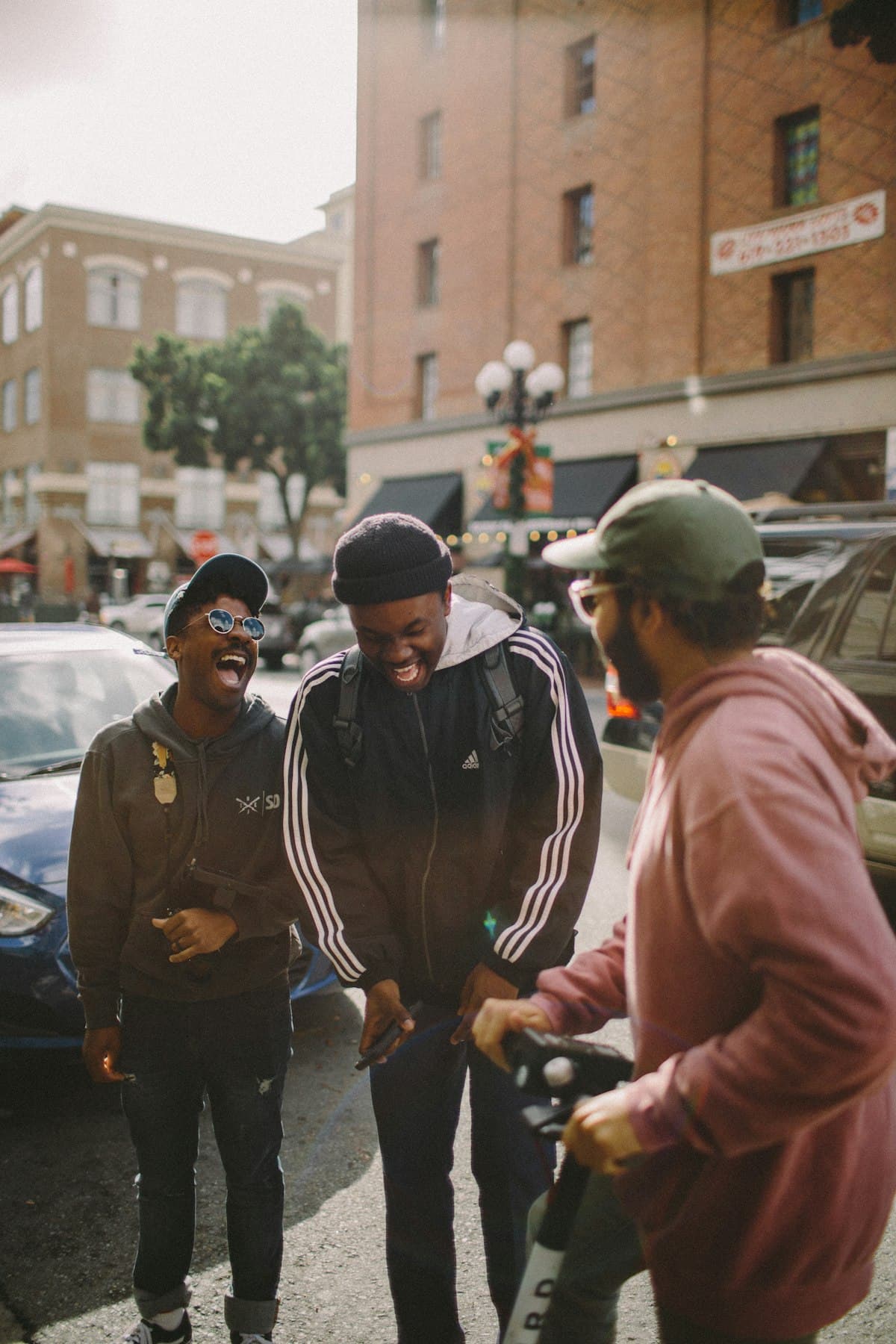 Three friends doubled over laughing on a city street