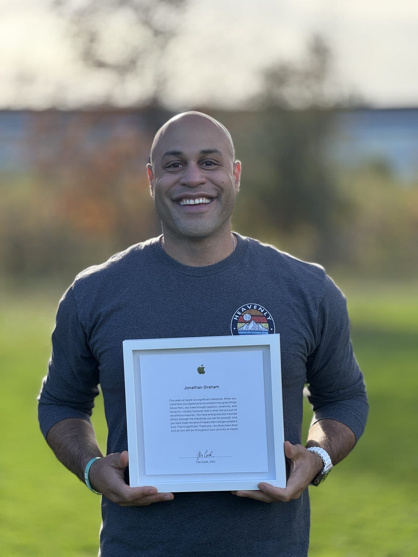 Jonathan holding his framed Apple anniversary letter, smiling