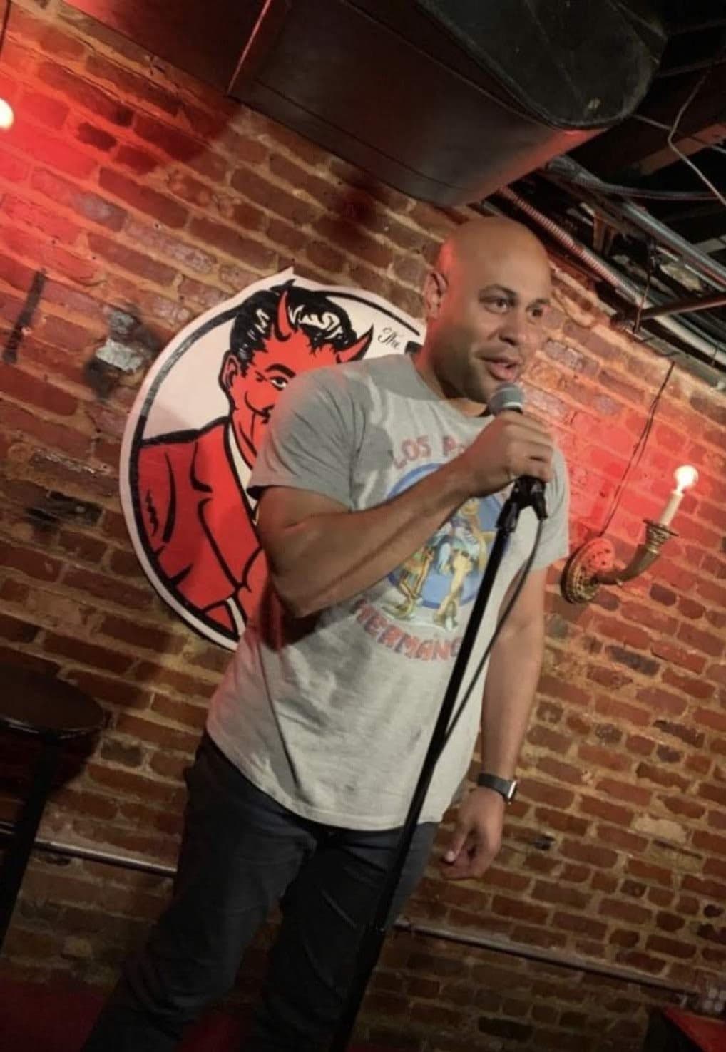 Jonathan on stage at an open mic, holding the microphone